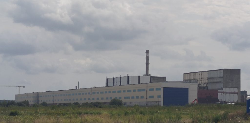 Foto des ehemaligen KKW mit Maschinenhalle im Vordergrund. Im Hintergrund sieht man Doppelblock 7/8 und Doppelblock 5/6 mit Abluftkamin.